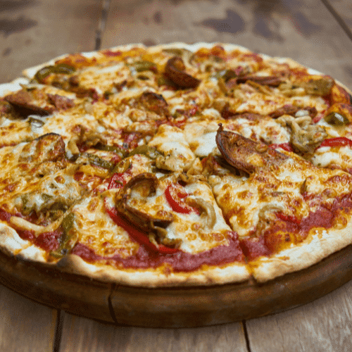 Close-up of a freshly baked pizza with cheese, peppers, and sausage on a wooden table.