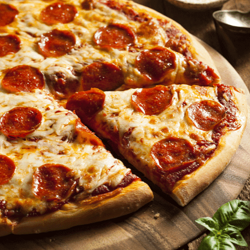 Pepperoni pizza on a wooden board with a slice being removed.